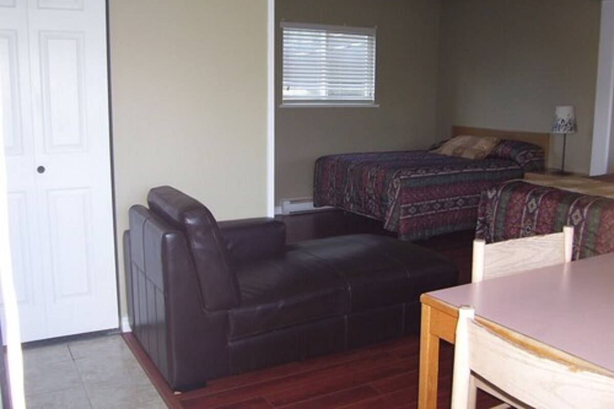 Habitación compacta con cama, una mesita, una silla y ventana con persianas.