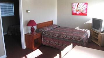 A hotel room with a bed, a TV, a lamp, and a painting on the wall.