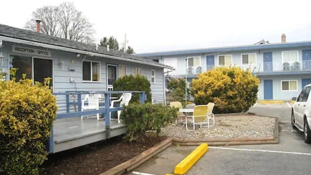 A motel with a reception desk, outdoor seating, and a parking area. - Beach Grove Motel (Delta)