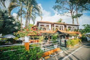 A traditional building with a tiled roof, surrounded by lush greenery and palm trees. - Hotel Villabosque Eco Boutique (Quepos)