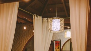 A cozy room with a bed, wooden furniture, and a hanging light fixture. - Hotel Villabosque Eco Boutique (Quepos)