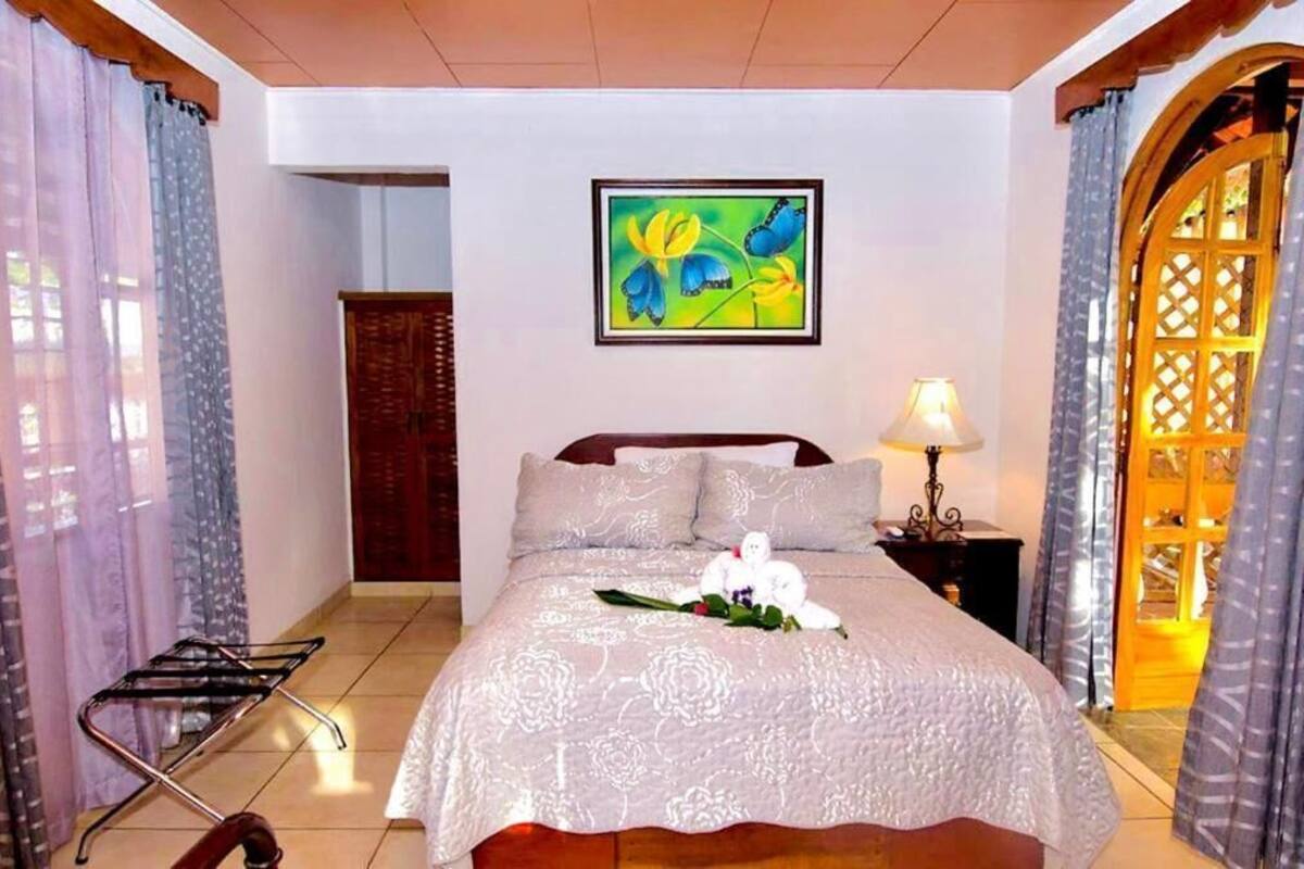 Une chambre d’hôtel comprenant un lit, une table de chevet, une lampe, un tableau mural et une porte ornée d’un motif en treillis.