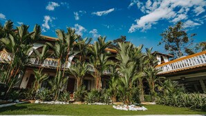 A resort with multiple buildings, palm trees, and a clear blue sky. - Hotel Villabosque Eco Boutique (Quepos)