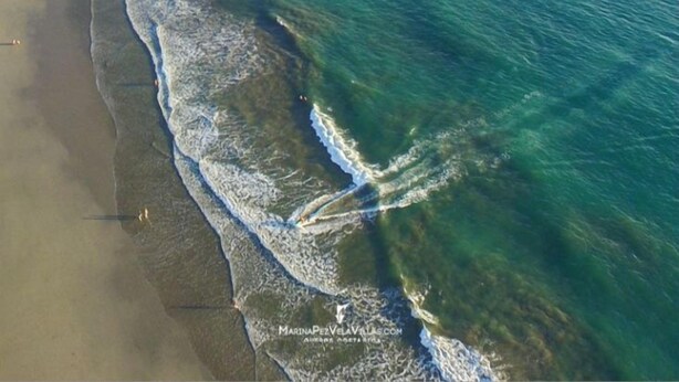 An aerial view of a coastal area with clear turquoise waters, a sandy beach, and a small island with dense greenery. - Hotel Villabosque Eco Boutique (Quepos)