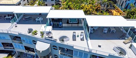 A modern hotel with multiple balconies, outdoor seating areas, and a rooftop pool.