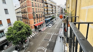 A street view with a building featuring a yellow facade and a balcony with a black railing. - Hostal Rias Bajas (Madrid)