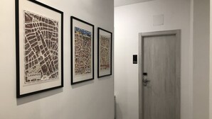 A hallway with three framed maps on the wall and a door with a number plate. - Hostal Rias Bajas (Madrid)