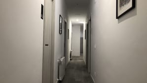 A narrow, well-lit hallway with doors on both sides, leading to a room at the end. - Hostal Rias Bajas (Madrid)