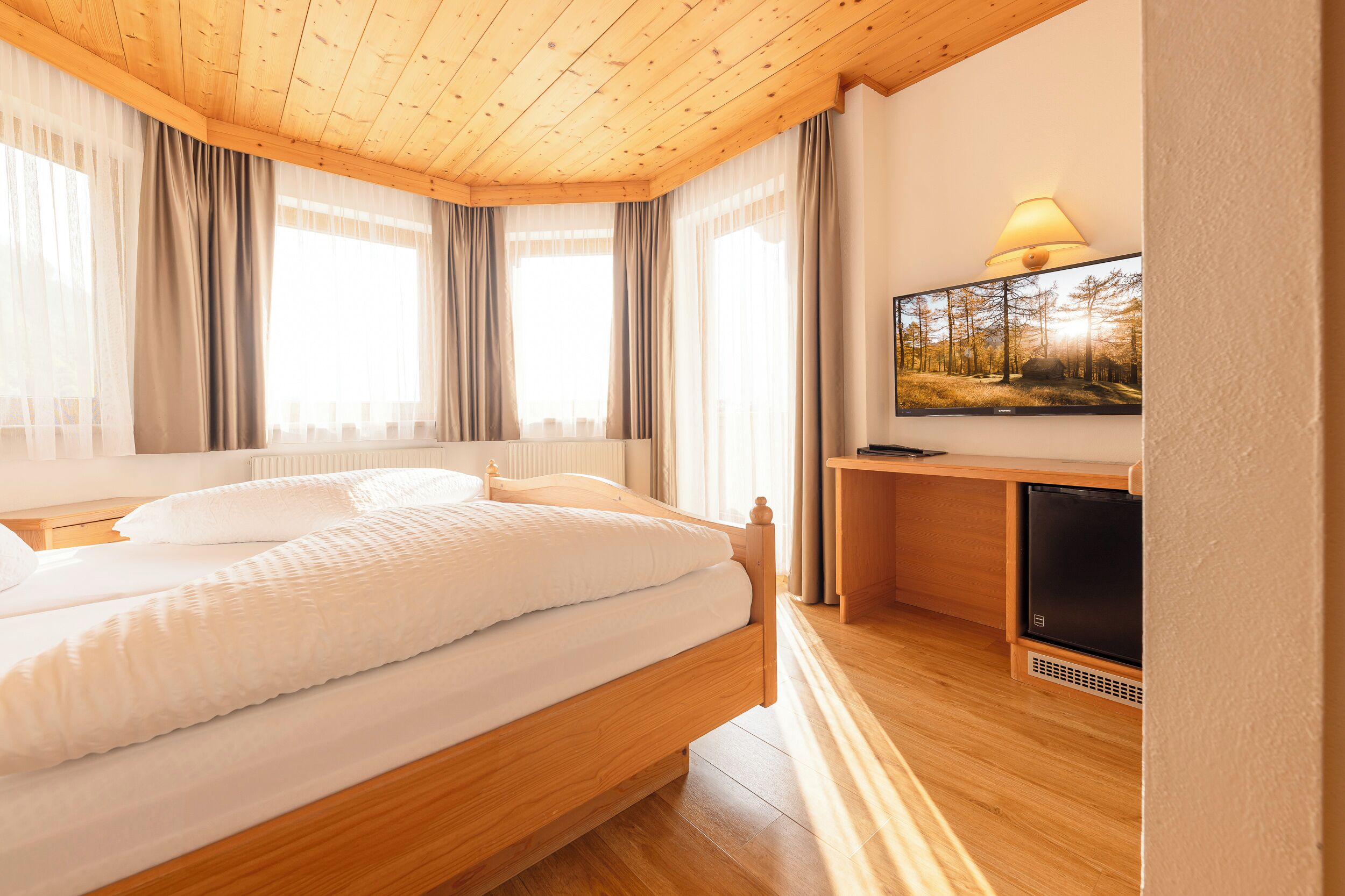 Una camera da letto con un letto di legno, una televisione e una scrivania.