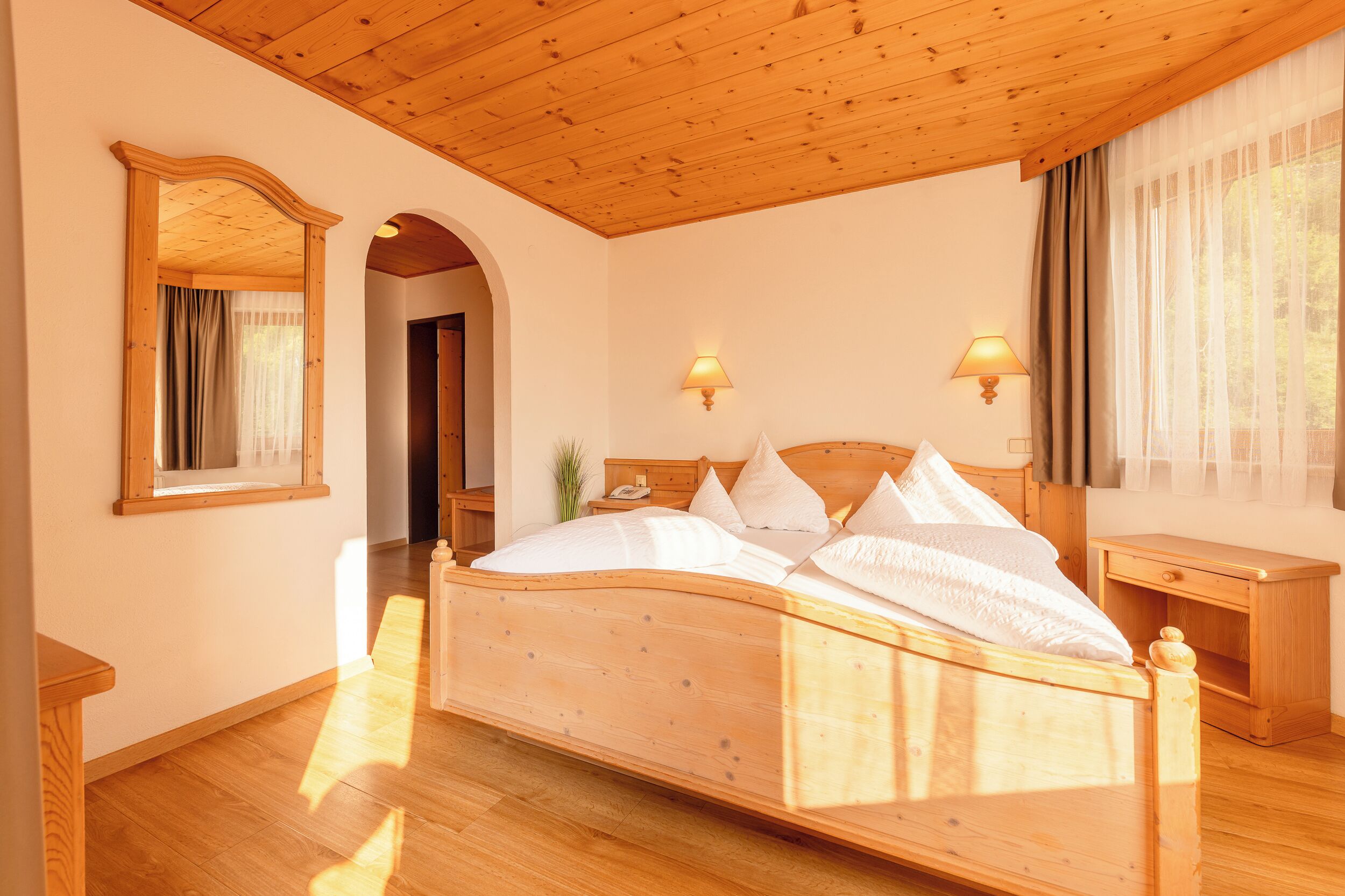 Ein Bett mit Holzrahmen, Kopfstütze, zwei Nachttischlampen und einem Nachttisch mit Lampe.