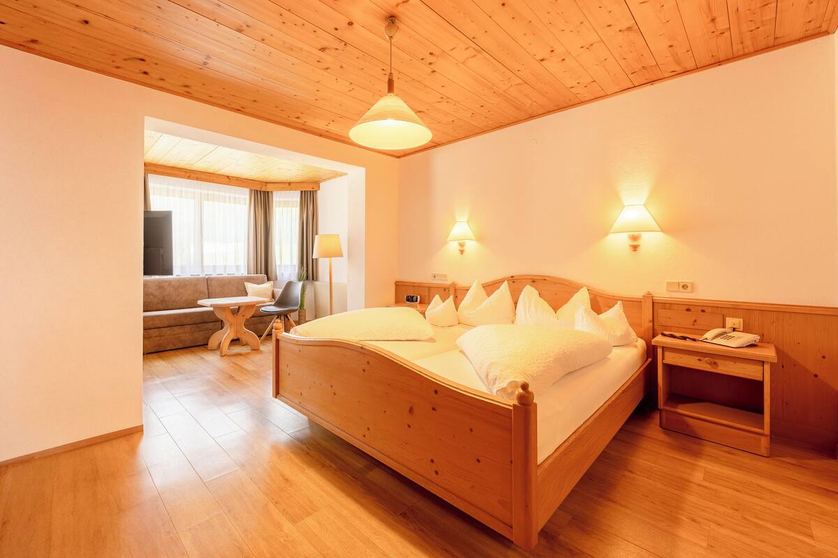 A wooden-framed room with a bed, bedside tables, and a lamp.