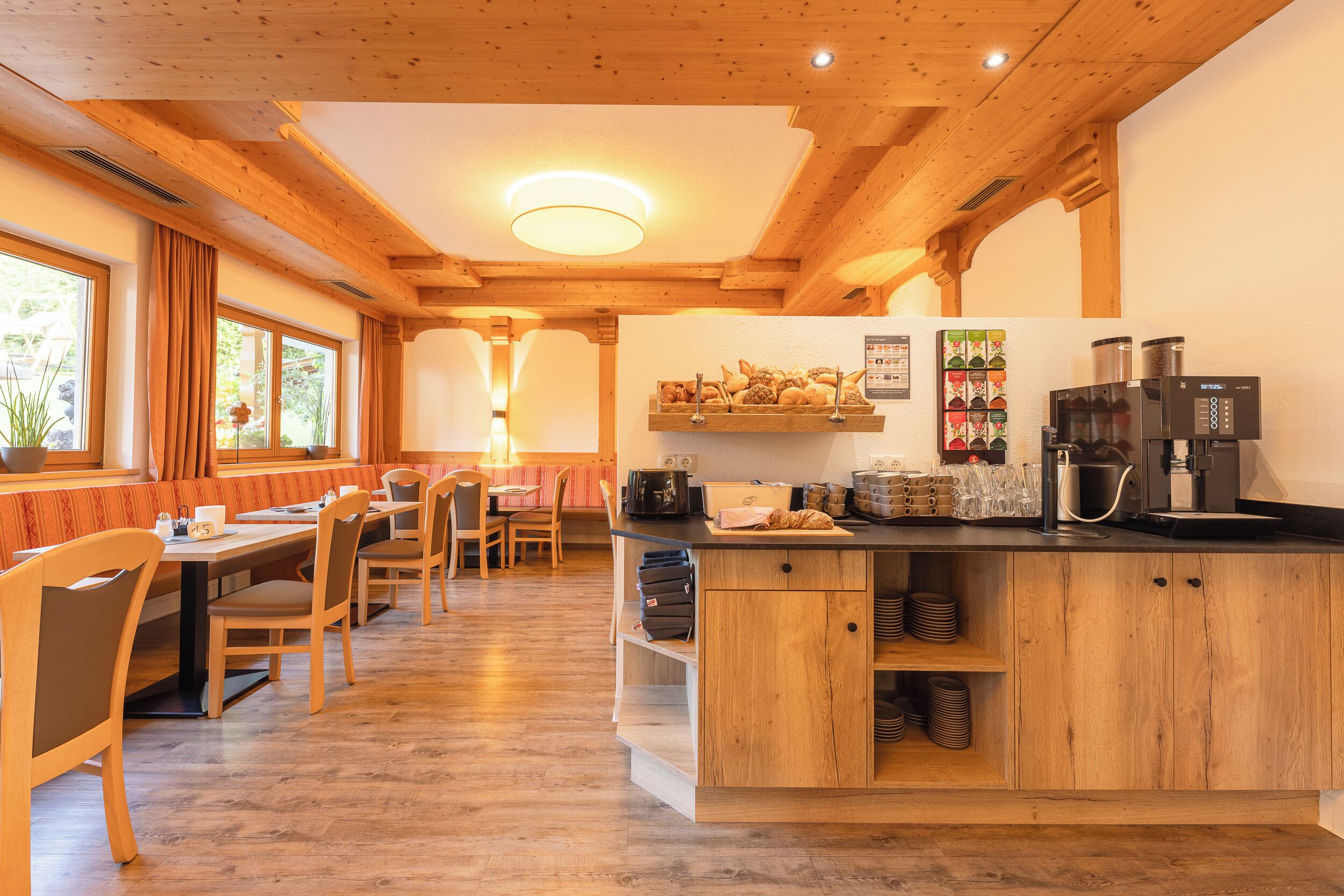 A cozy restaurant with wooden furniture, a central island with a coffee machine, and a menu board above the counter.