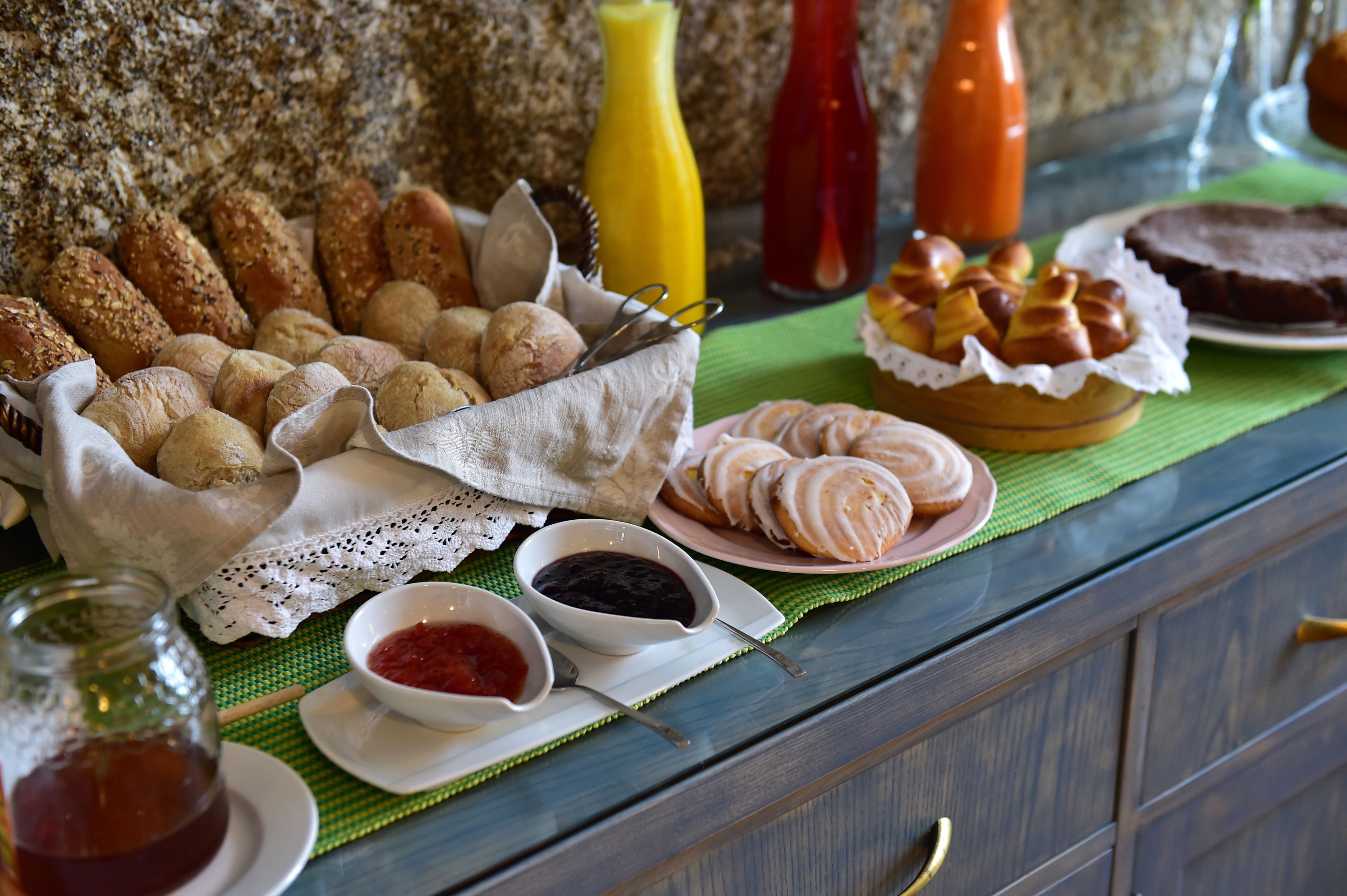 Een buffettafel met verschillende broden, gebak en toevoegingen.