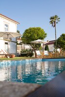 Una piscina al aire libre, sombrillas, sillones reclinables de piscina