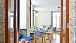 Una habitación acogedora con piso de madera, sillas a rayas, un sofá azul y una mesita pequeña.