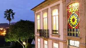 Un edificio con un amplio ventanal de vitrales, un balcón y una palmera al fondo.
