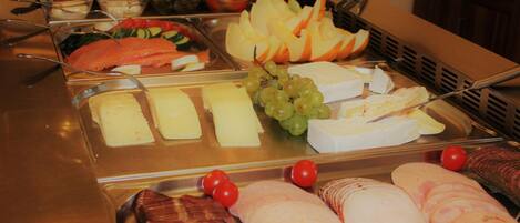 A buffet with various food items including salmon, cheese, grapes, and tomatoes.