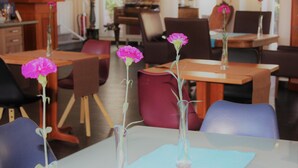 Um quarto com mesas e cadeiras, algumas com vasos de flores.