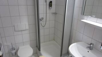 Een badkamer met een douche met glazen wand, een toilet en een wastafel.