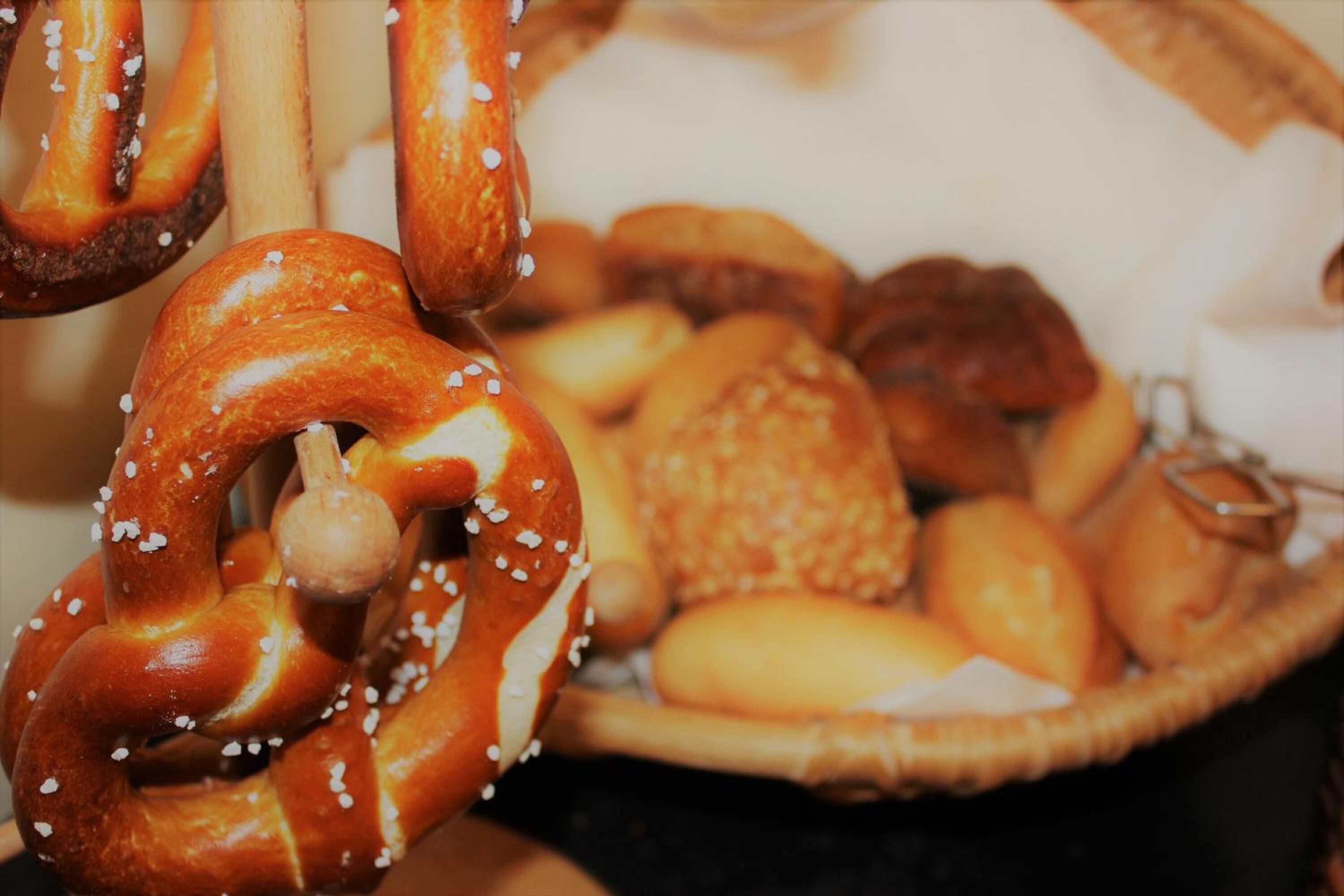 Diverse gebakken producten, waaronder pretzels en brood, gepresenteerd in een mand.