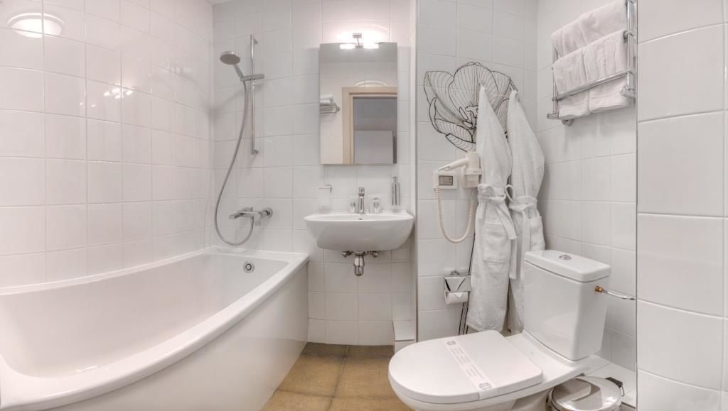 Et moderne badeværelse med badekar, håndvask, toilet og bruser.