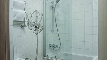 Un baño moderno con cabina de ducha de vidrio, inodoro blanco y bañera de hidromasaje con mampara de vidrio.