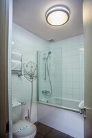 Un baño moderno con cabina de ducha de vidrio, inodoro blanco y bañera de hidromasaje con mampara de vidrio.