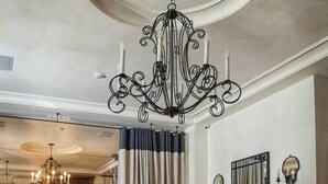 Una habitación amplia con un candelabro, un jarrón de flores y una consola decorada con objetos ornamentales.