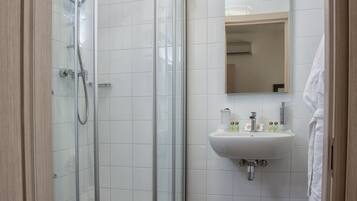A modern bathroom with a glass shower enclosure, a white sink, and a toilet.