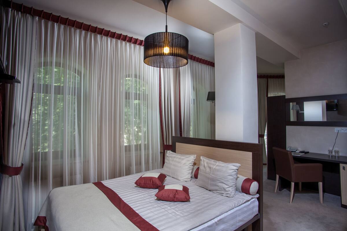 A hotel room with a large bed, a desk, and a chair.