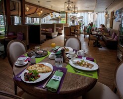 Un comedor con mesas y sillas de madera, y una selección de alimentos para el desayuno.