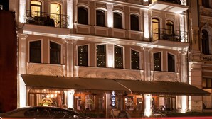 Un hotel de varios pisos con arquitectura ornamentada, varios balcones e iluminacion en las ventanas.