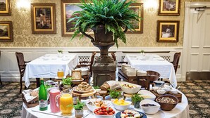 Een ontbijtbuffet met diverse gerechten en een grote varens als decoratie.