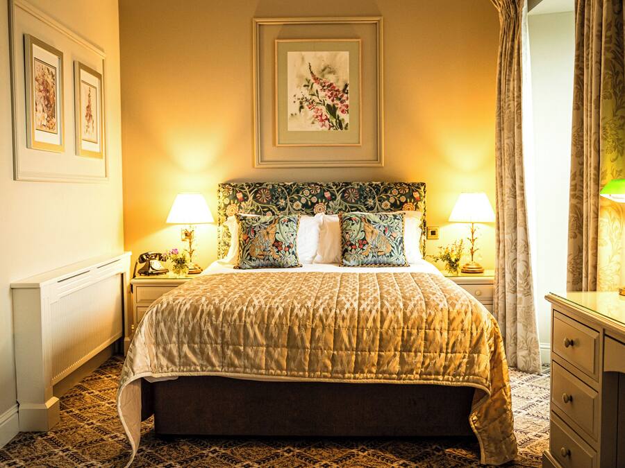 A hotel room with a large bed, two bedside lamps, a nightstand, and a dresser.