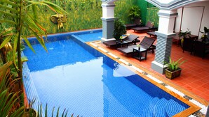 A swimming pool with a tiled edge, surrounded by a patio area with seating and plants. - Parent Heritage Angkor Villa (Siem Reap)