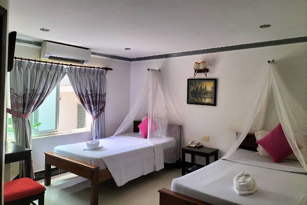 Quarto com duas camas, uma mesinha, uma cadeira e um criado-mudo.