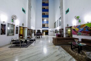 A spacious living area with a high ceiling, a dining table, sofas, and a large rug. - Oritel Service Apartments (Mumbai)