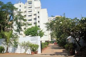 A multi-story residential building with a gated entrance, surrounded by potted plants and trees. - Oritel Service Apartments (Mumbai)