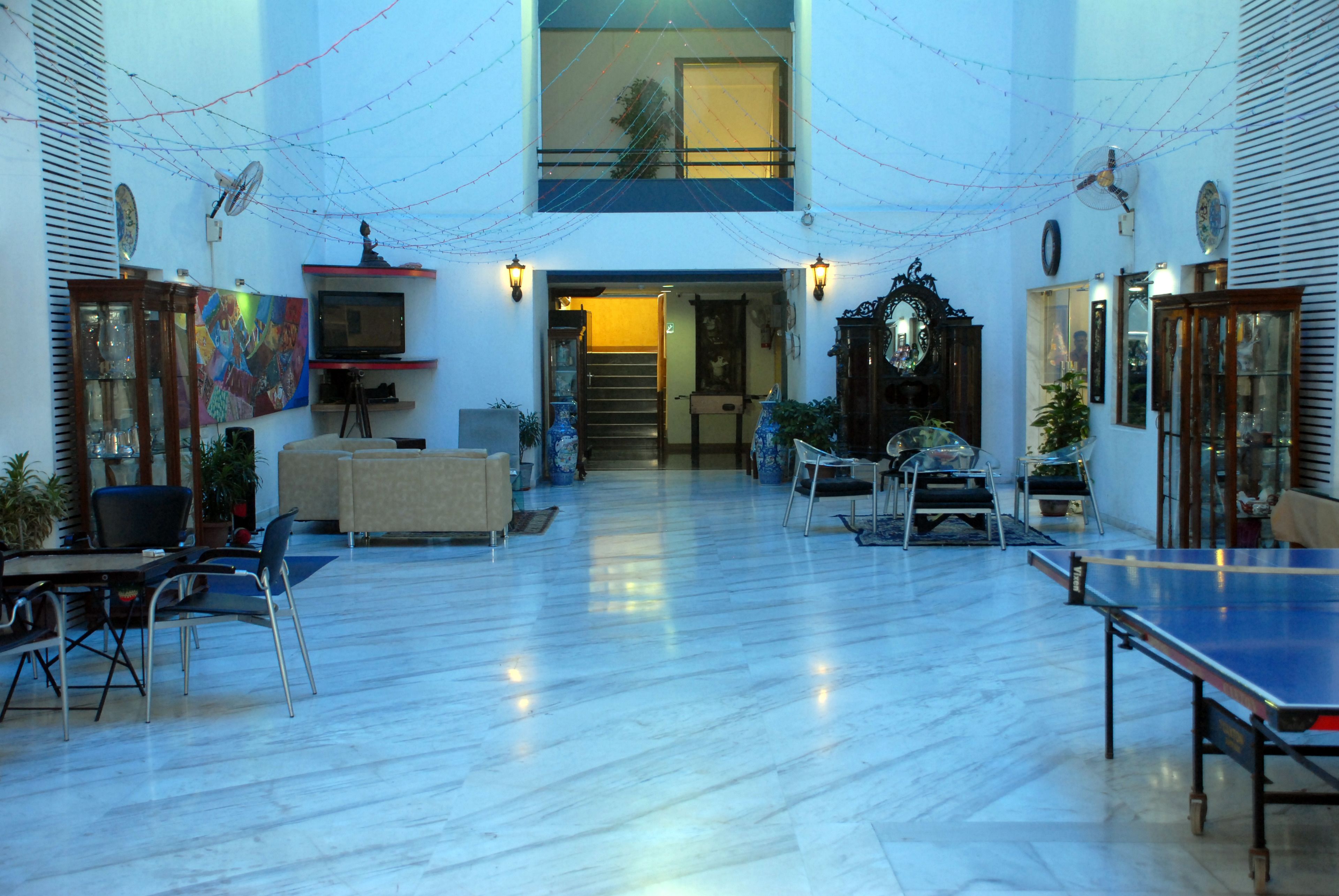 A spacious indoor area with a ping pong table, seating, and a staircase leading to an upper level.