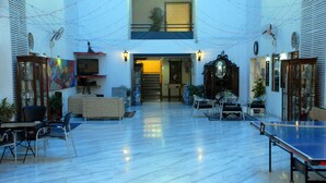 Un espacio interior amplio con mesa de ping-pong, asientos y una escalera que sube a un nivel superior.