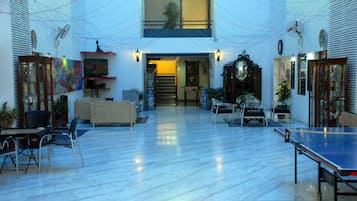 A spacious indoor area with a ping pong table, seating, and a staircase leading to an upper level.