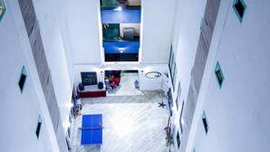 Un atrio con techos altos, una zona de estar central, una mesa de ping pong y un escenario pequeño.