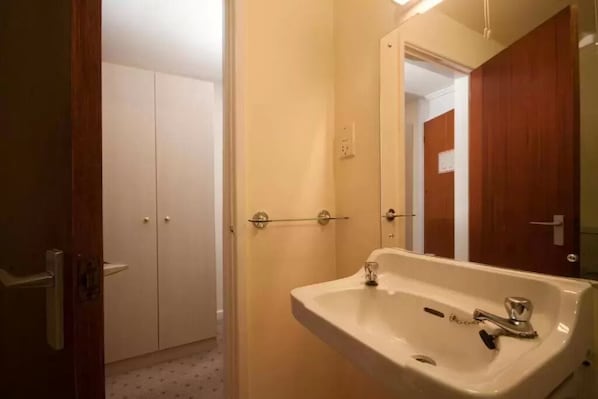 A bathroom with a sink, mirror, and wooden door. - Norfolk Hotel (St. Helier)