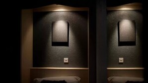 Una habitación de hotel con una cama, una lámpara de pared y un enchufe.