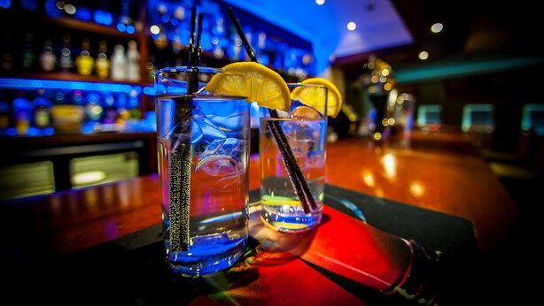 Una zona de bar con dos vasos de una bebida azul, adornados con rodajas de limón y una servilleta roja.
