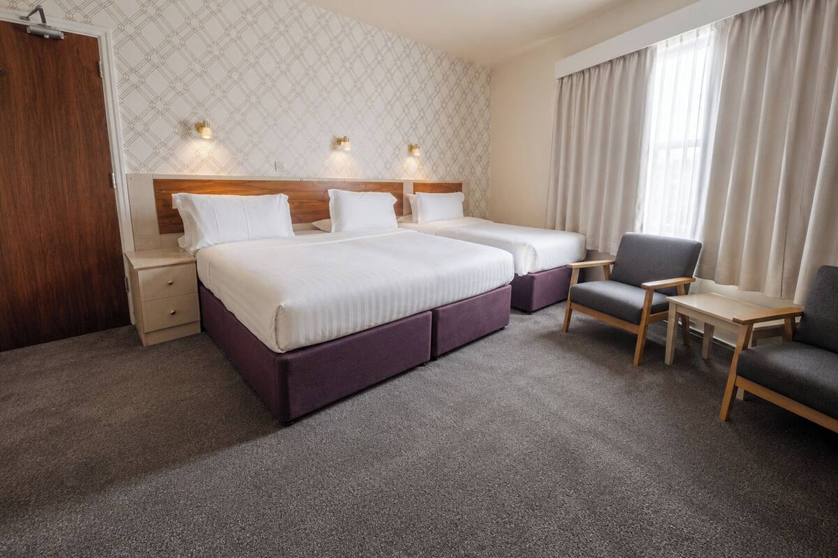 Una habitación de hotel con dos camas, un escritorio, una silla y un armario.