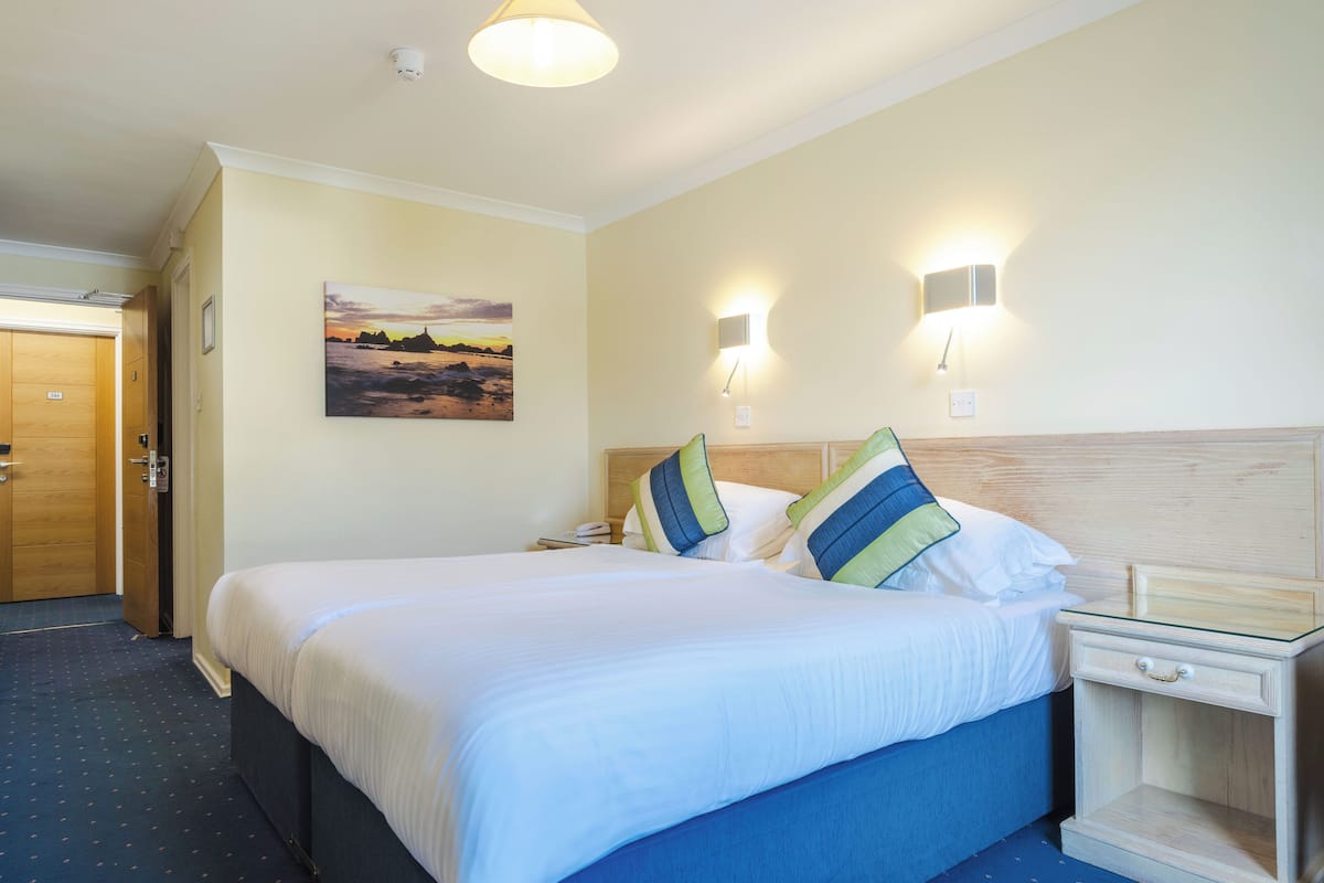 Habitación de hotel con una cama grande, dos mesitas de noche, una lámpara de pared y un cuadro en la pared.