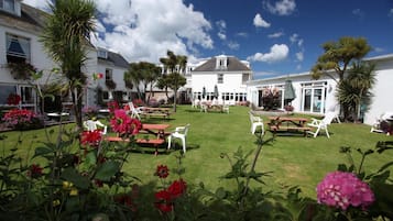 Enjoy dining and socializing in the beautifully landscaped outdoor area with seating arrangements and tables.