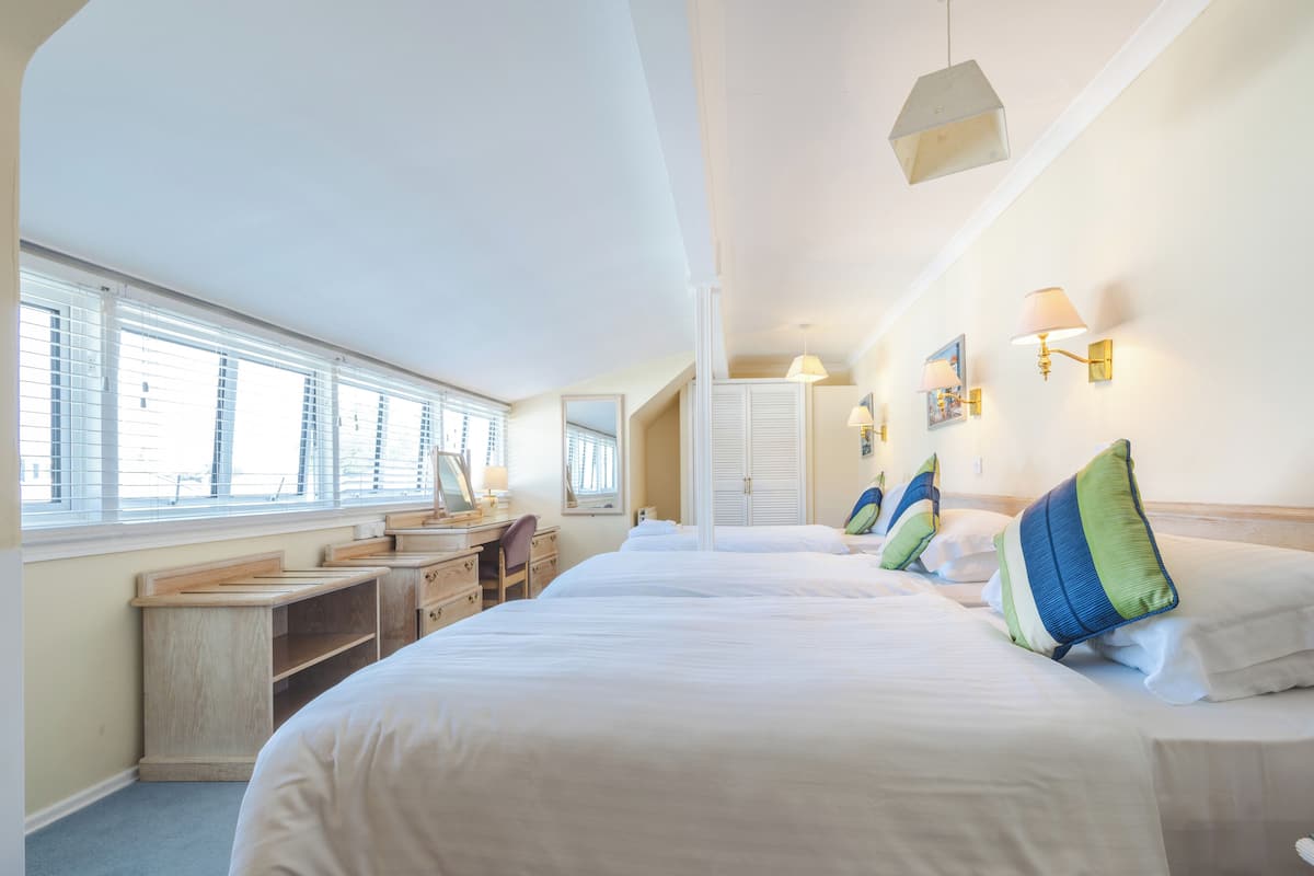 Una habitación de hotel con una cama grande, un escritorio y una ventana con persianas.