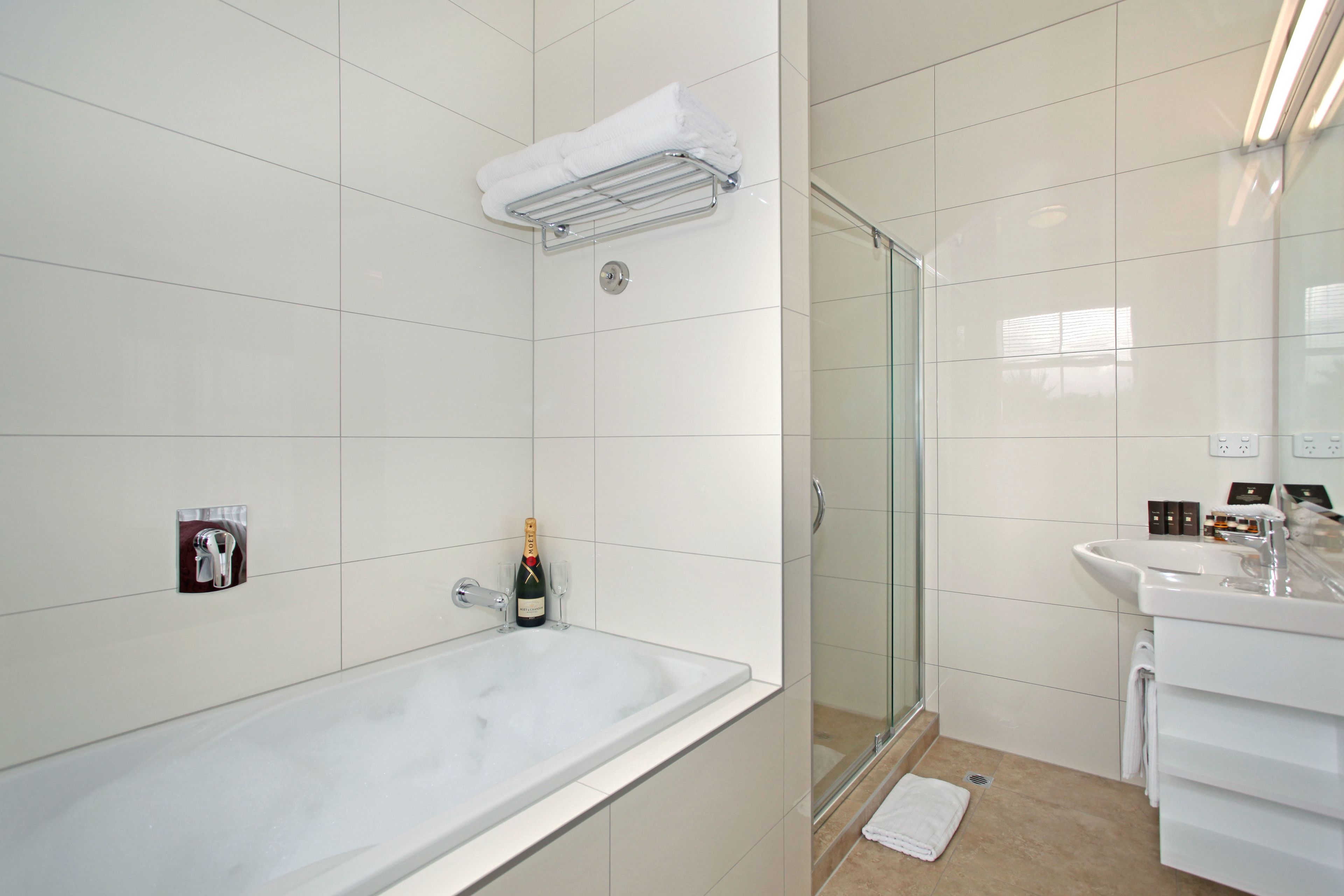 Un bagno moderno con una grande vasca, un box doccia in vetro e un lavandino bianco con specchio.